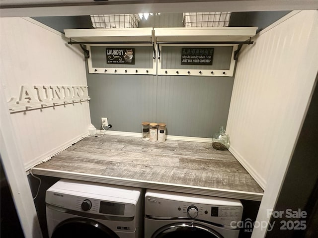 clothes washing area featuring baseboards, wood finished floors, washer and dryer, and laundry area