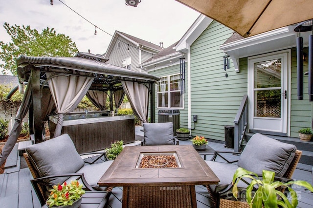 wooden deck with a gazebo, a fire pit, a hot tub, and central AC