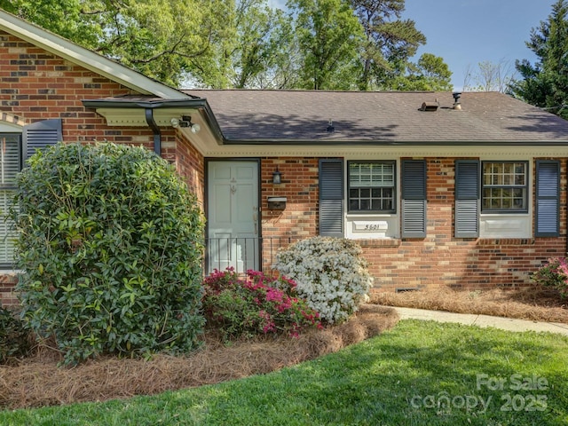 view of front of home with brick siding and roof with shingles