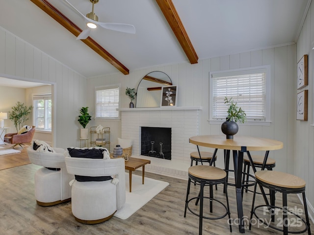 living area featuring ceiling fan, lofted ceiling with beams, wood finished floors, and a fireplace