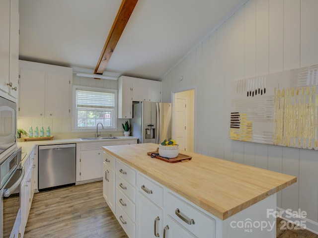 kitchen with light wood-style flooring, a sink, vaulted ceiling with beams, butcher block countertops, and appliances with stainless steel finishes