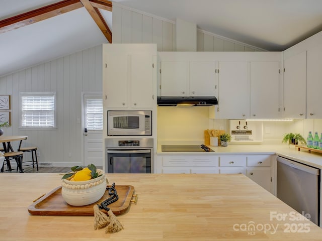 kitchen featuring white cabinets, vaulted ceiling, light countertops, under cabinet range hood, and appliances with stainless steel finishes
