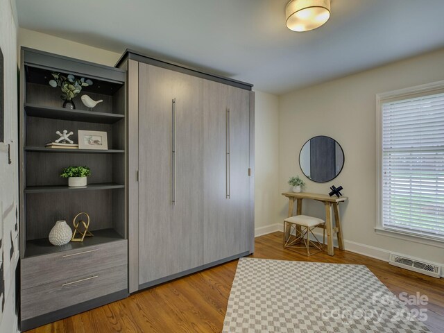 interior space featuring baseboards, wood finished floors, and visible vents