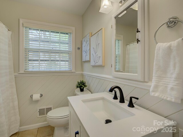 full bathroom with a wainscoted wall, tile patterned floors, visible vents, toilet, and vanity