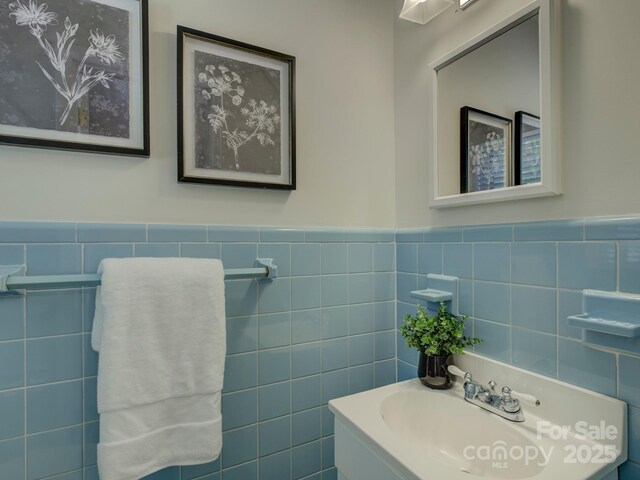 bathroom featuring tile walls, a wainscoted wall, and a sink