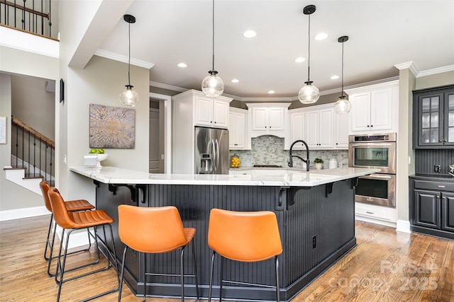 kitchen featuring stainless steel appliances, ornamental molding, light wood-style floors, tasteful backsplash, and white cabinetry