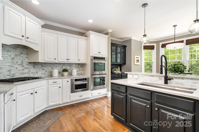 kitchen with white cabinets, gas cooktop, stainless steel double oven, and a sink