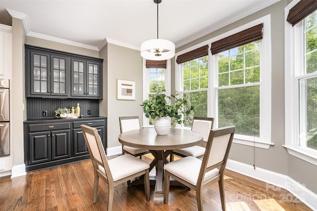 dining room with wood finished floors, crown molding, and baseboards