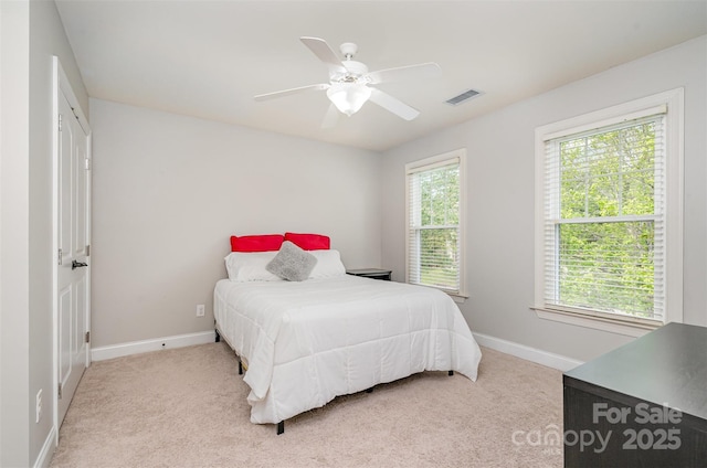 carpeted bedroom featuring baseboards, visible vents, ceiling fan, and multiple windows