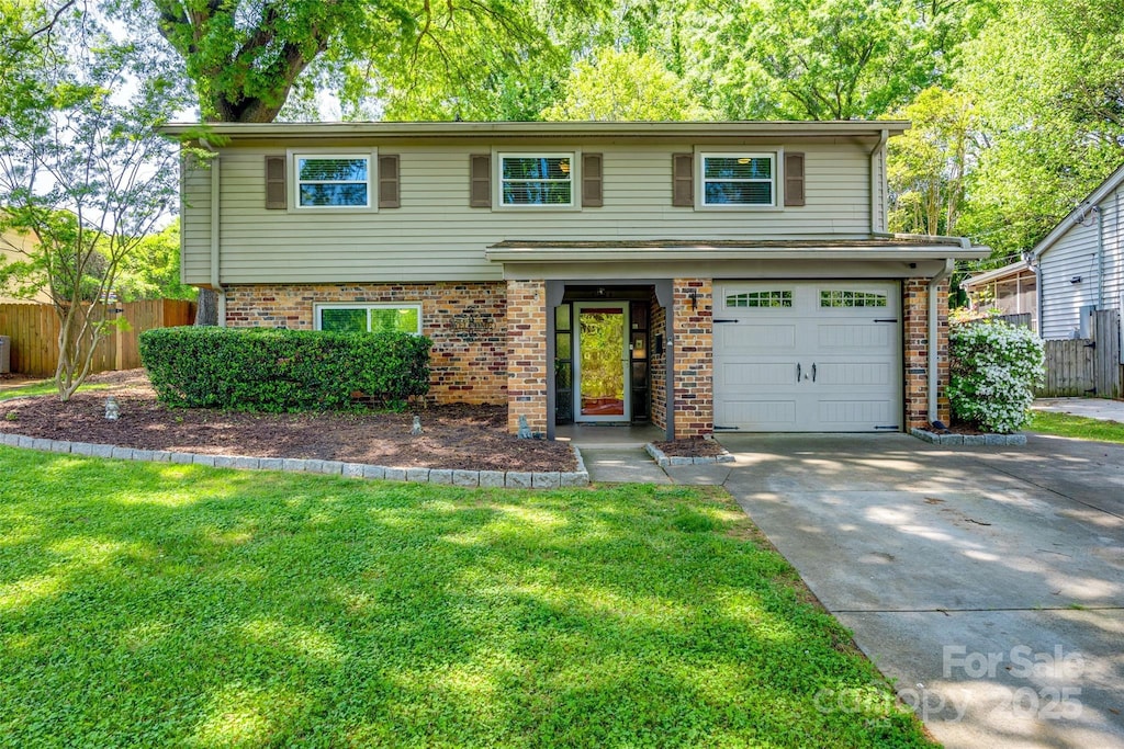 view of front of property featuring driveway, fence, brick siding, an attached garage, and a front yard