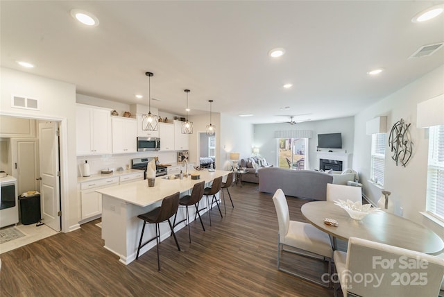 15520 Capps Rd, Charlotte, NC 28278 - kitchen featuring stainless steel appliances, a kitchen bar, dark wood-type flooring, a sink, and white cabinets