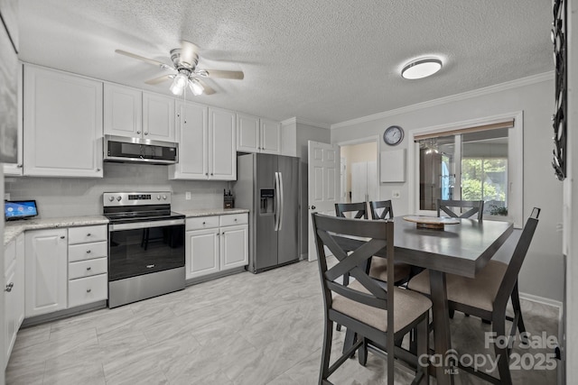 16070 Palawan Ct, Tega Cay, SC 29708 - kitchen with stainless steel appliances, white cabinetry, crown molding, a textured ceiling, and ceiling fan