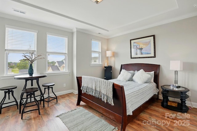 bedroom with baseboards, crown molding, wood finished floors, and visible vents
