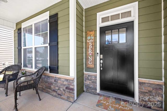 doorway to property with covered porch and stone siding
