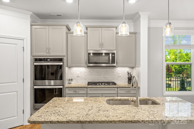 kitchen featuring crown molding, appliances with stainless steel finishes, a sink, a kitchen island with sink, and decorative backsplash