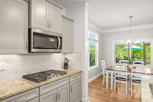 kitchen featuring crown molding, light wood-type flooring, tasteful backsplash, and stainless steel appliances