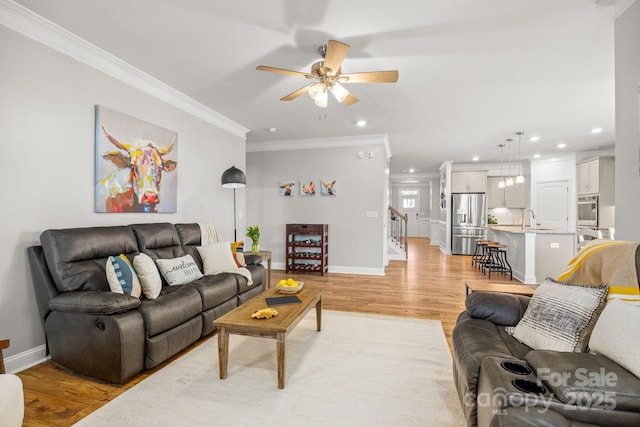living room with light wood-style floors, recessed lighting, a ceiling fan, baseboards, and ornamental molding