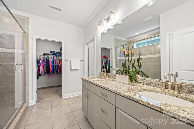 full bathroom with visible vents, a sink, a walk in closet, and a shower stall