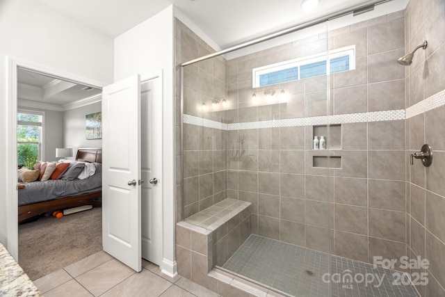 ensuite bathroom featuring a tile shower, tile patterned floors, ornamental molding, and ensuite bath