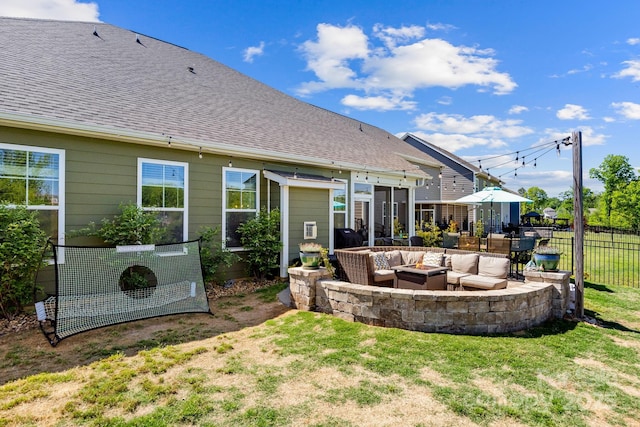 rear view of house with roof with shingles, a patio area, fence, an outdoor living space with a fire pit, and a yard