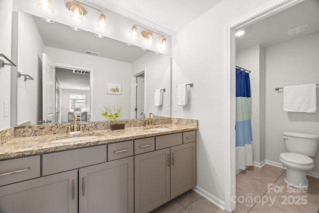 full bathroom with double vanity, a sink, tile patterned floors, and toilet