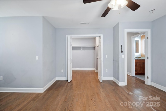 1592 Farmington Hills Dr, Conover, NC 28613 - unfurnished bedroom featuring wood finished floors, visible vents, a walk in closet, a closet, and baseboards