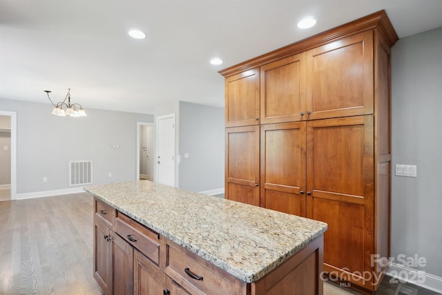 1592 Farmington Hills Dr, Conover, NC 28613 - kitchen featuring brown cabinets, light wood-style flooring, visible vents, and light stone counters