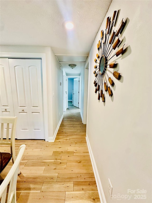 hall featuring light wood-type flooring and baseboards