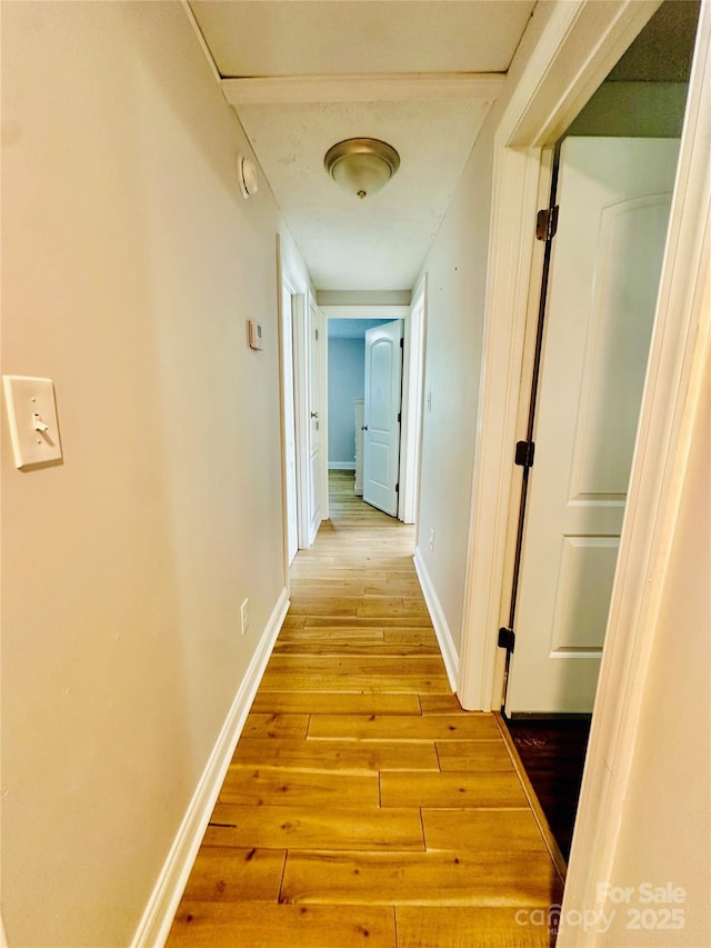 hallway with light wood-type flooring and baseboards