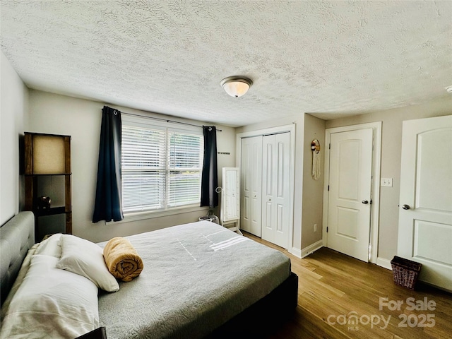 bedroom featuring wood finished floors, a closet, a textured ceiling, and baseboards