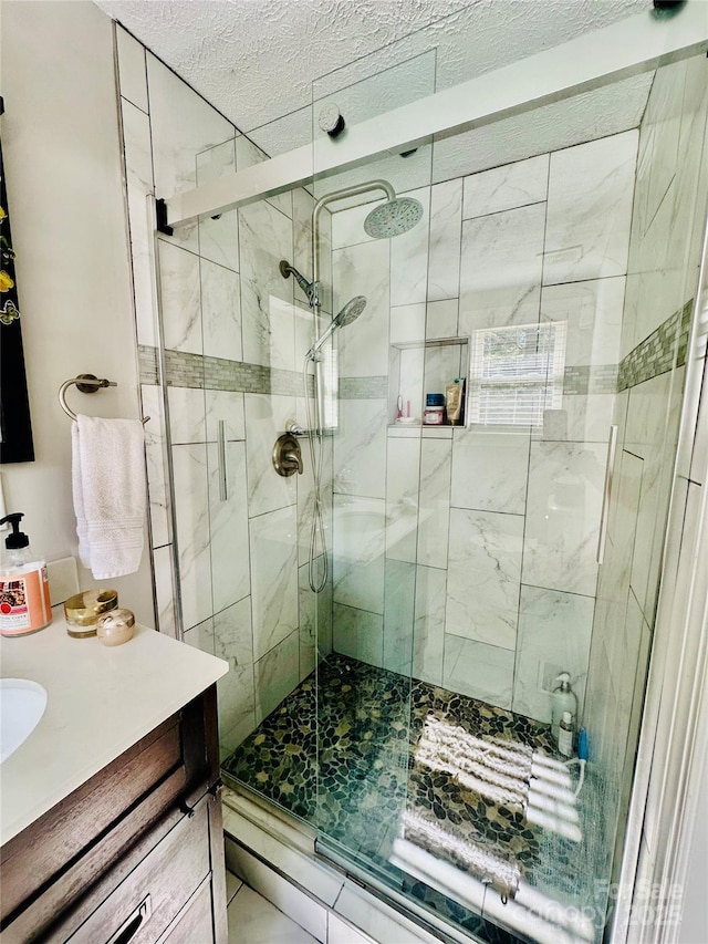 bathroom with a shower stall, vanity, and a textured ceiling
