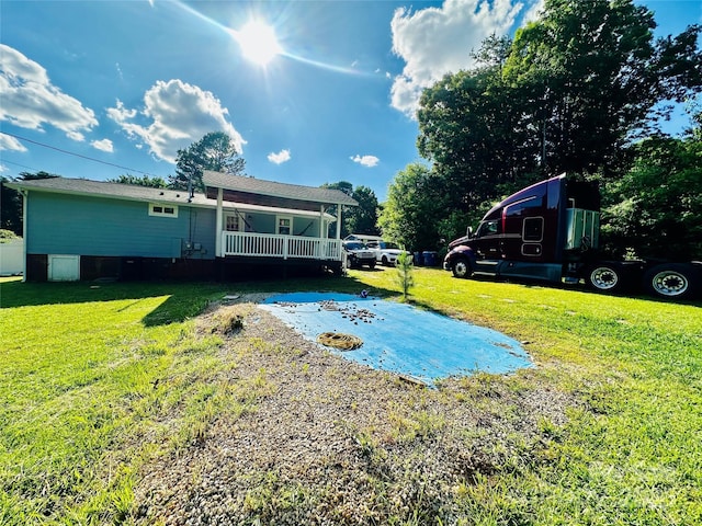 view of green lawn featuring covered porch