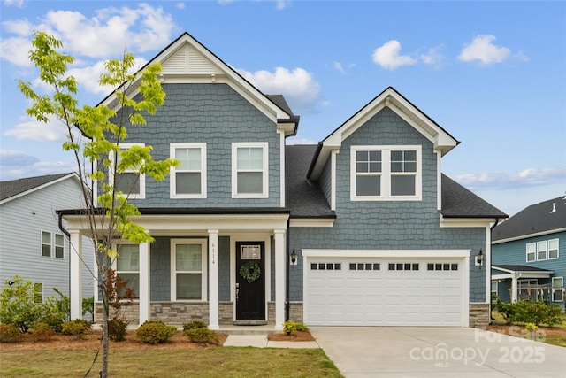 view of front of home featuring concrete driveway, stone siding, covered porch, and a garage
