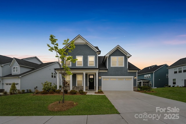 view of front facade with a lawn, an attached garage, driveway, and stone siding