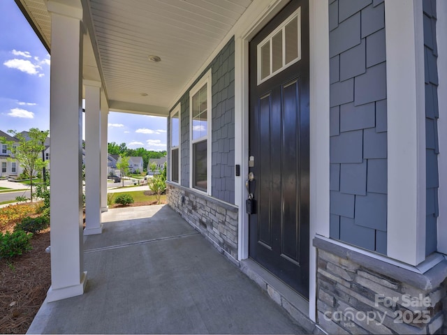 entrance to property featuring a porch and stone siding