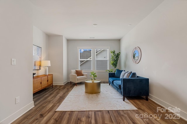 living area featuring visible vents, wood finished floors, and baseboards