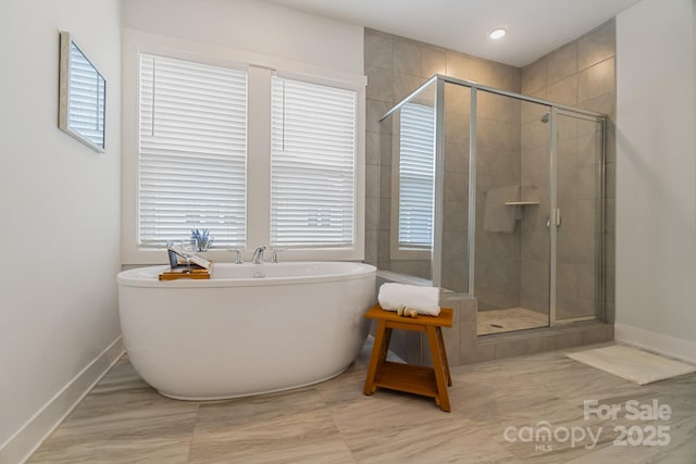 bathroom featuring a soaking tub, baseboards, and a shower stall
