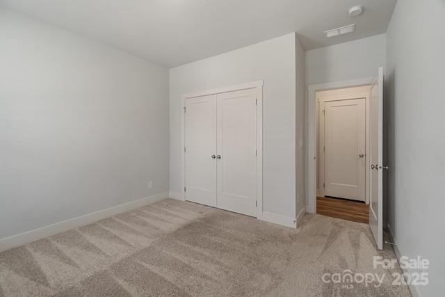 unfurnished bedroom featuring baseboards, carpet flooring, and a closet