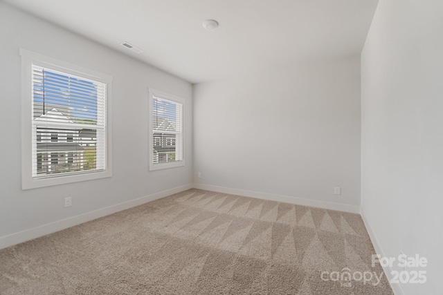 empty room with visible vents, light carpet, and baseboards