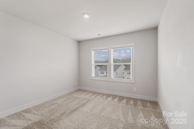 spare room with visible vents, baseboards, and light colored carpet