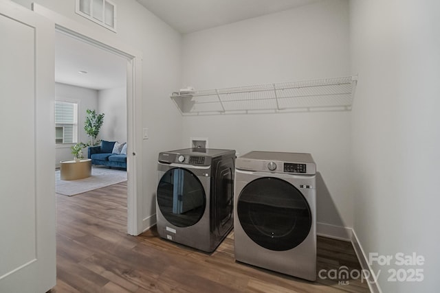 laundry area featuring washing machine and clothes dryer, baseboards, visible vents, wood finished floors, and laundry area