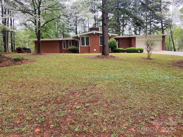 view of front of property with a chimney, concrete driveway, brick siding, and a front lawn