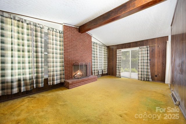 unfurnished living room featuring wooden walls, carpet floors, and a brick fireplace