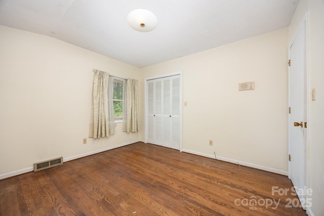 unfurnished bedroom featuring wood finished floors, baseboards, and a closet
