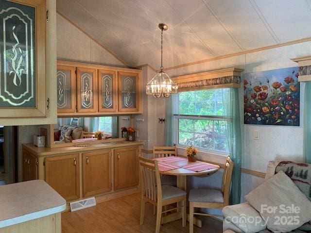dining area with a chandelier, visible vents, light wood-style flooring, and lofted ceiling