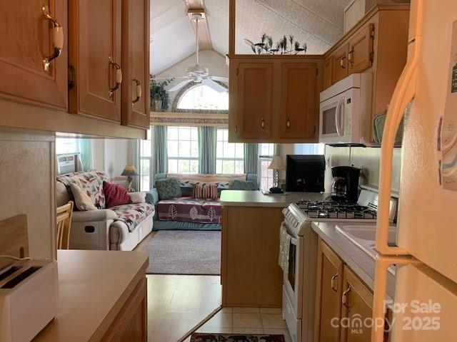 kitchen with ceiling fan, lofted ceiling with beams, white appliances, brown cabinetry, and light countertops