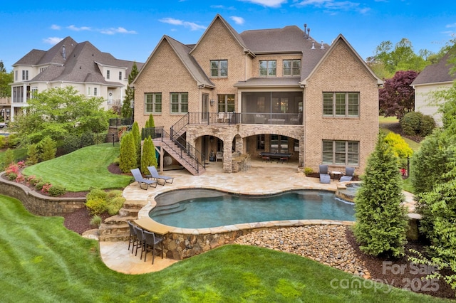 rear view of property featuring a sunroom, outdoor dry bar, a patio area, brick siding, and stairs