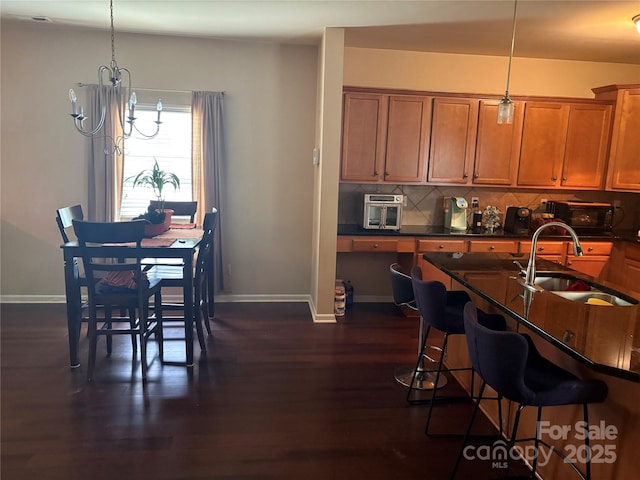 1104 Valley St, Statesville, NC 28677 - kitchen featuring a sink, baseboards, brown cabinetry, and a breakfast bar area