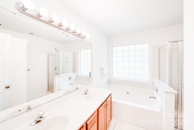 full bathroom with double vanity, a stall shower, a sink, and a bath