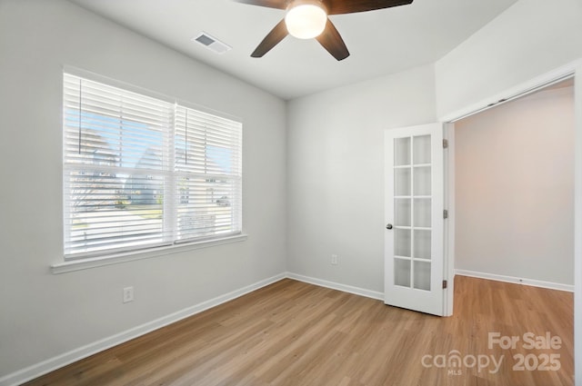 empty room featuring a ceiling fan, french doors, wood finished floors, and visible vents